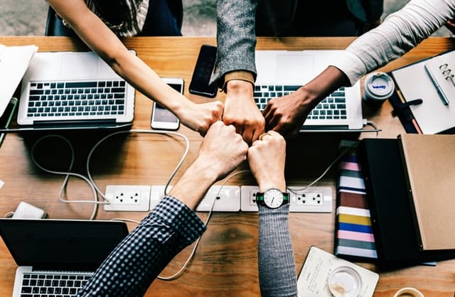 People fist-bumping across a table during a meeting