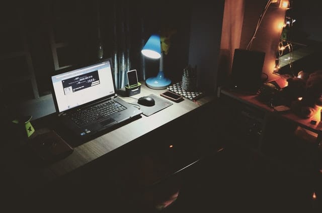 Empty desk in the dark with a single lamp