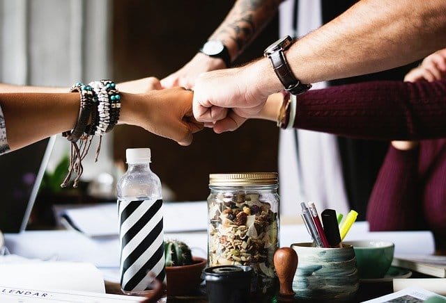 group of people fist bumping over a table